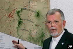 FILE - The Rev. Robin Hoover, who is president of the Humane Borders group, explains a map showing migrant deaths (red dots) on the Arizona desert and warning that crossing through the desert is extremely dangerous, during a news conference in Mexico City