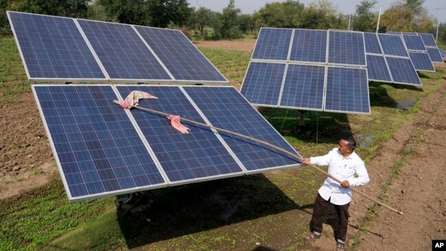 Farmer Pravinbhai Parmar cleans a solar panel installed at a farm in Dhundi village of Kheda district in western Indian Gujarat state, India, Jan. 13, 2023.