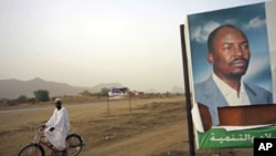 A man cycles past a gubernatorial election campaign billboard of NCP candidate for the governor's post Ahmed Haroun at Kadogli town, South Kordofan State, May 1, 2011