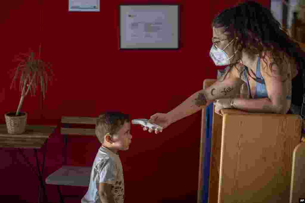 Hugo, 3, has his temperature taken by a teacher as he arrives at Cobi kindergarten in Barcelona, Spain.