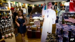 A tourist passes cutout of Pope Francis at Making History, a Philadelphia themed gift shop Philadelphia, Aug. 10, 2015. The cutouts have been popping up in areas around the region more than a month ahead of the pope's scheduled visit.