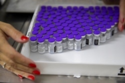 FILE - A health worker holds a tray with vials of the Pfizer vaccine for COVID-19 during a priority vaccination program at a community medical center in Sao Paulo, Brazil, May 6, 2021.