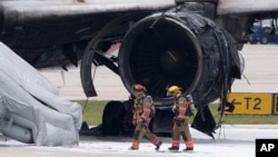 Firefighters walk past the burned-out engine of a Dynamic International Airways Boeing 767 at Fort Lauderdale/Hollywood International Airport in Dania Beach, Fla., Oct. 29, 2015.