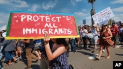 FILE - Supporters of Deferred Action for Childhood Arrivals chant slogans and carry signs in Los Angeles, Sept. 4, 2017.