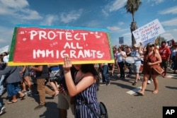 FILE - Supporters of the Deferred Action for Childhood Arrivals, or DACA chant slogans and carry signs while joining a Labor Day rally in downtown Los Angeles.