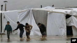 Syrian refugee boys make their way in flooded water at a temporary refugee camp in the Lebanese town of Al-Faour, near the border with Syria, January 8, 2013.