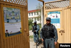 Afghan policemen stand guard at a gate of a voter registration center for the upcoming parliamentary and district council elections in Kabul, Afghanistan, April 23, 2018.