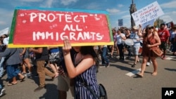 FILE - Supporters of the Deferred Action for Childhood Arrivals, or DACA chant slogans and carry signs while joining rally in downtown Los Angeles, Sept. 4, 2017.