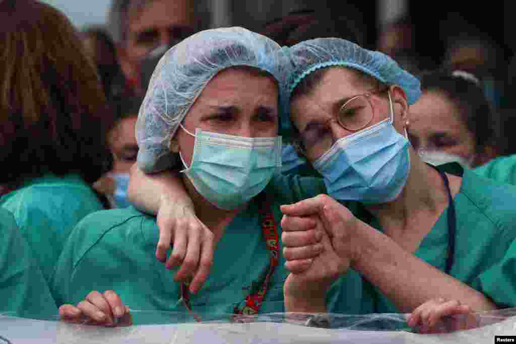 Health workers react during a tribute for their co-worker Esteban, a male nurse who died of the coronavirus disease, outside the Severo Ochoa Hospital in Leganes, Spain.