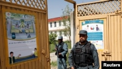 Afghan policemen stand guard at a gate of a voter registration center for the upcoming parliamentary and district council elections in Kabul, Afghanistan, April 23, 2018.