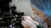 FILE - A researcher installs a fine glass pipette into a microscope in preparation for working with embryos at a lab in Shenzhen in southern China's Guandong province, Oct. 9, 2018. 