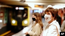 Passengers with face masks wait for a train at the Alexanderplatz underground station in Berlin, Germany, where like many other countries, it is mandatory to wear a cover for mouth and nose at public transport.