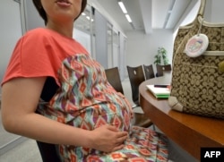 Seorang perempuan hamil sedang bekerja di kantornya di Tokyo, 2 Juli 2013.