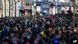 FILE - Crowds of shoppers walk under the Christmas lights in Regent Street, in London, Saturday, Dec. 12, 2020. 