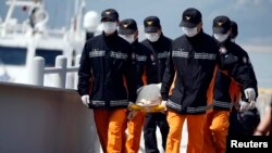 Para petugas penyelamat menggotong jenazah para penmupang kapal Sewol yang tenggelam di pelabuhan Jindo (20/4). (Reuters/Kim Hong-Ji)