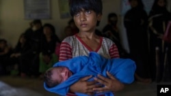 Rohingya Muslim girl Afeefa Bebi, who crossed over from Myanmar into Bangladesh, holds her baby brother. Rohingya have been fleeing persecution in Buddhist-majority Myanmar for decades, and many who have made it to safety in other countries still face a precarious existence. (AP Photo/Dar Yasin)