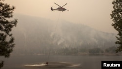 A helicopter gathers water from Blue Lake while fighting the Okanogan Complex fire in the Sinlahekin Wildlife Area near Loomis, Washington, Aug. 25, 2015.