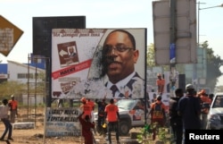 FILE - Opponents of Senegal's president Macky Sall vandalize a poster for the upcoming presidential elections in Thies, Senegal, Feb. 3, 2019.