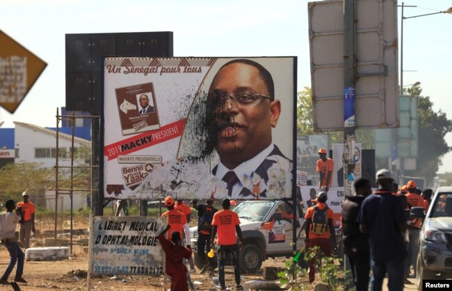 FILE - Opponents of Senegal's president Macky Sall vandalize a poster for the upcoming presidential elections in Thies, Senegal, Feb. 3, 2019.
