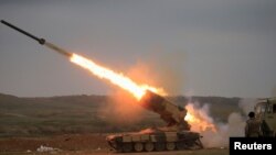 An Iraqi Army officer (R) uses his mobile phone to film a rocket launched towards Islamic State militants during a battle with Islamic State militants in Mosul, Iraq, March 3, 2017. 