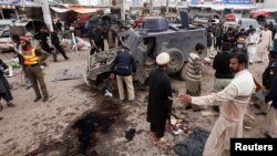 FILE: The Pakistani Taliban, fighting to topple the government through terrorist attacks, is dividing. In Peshawar, a sprawling city on Pakistan's border with Afghanistan, police gather evidence after a suicide bombing that killed at least nine bystanders