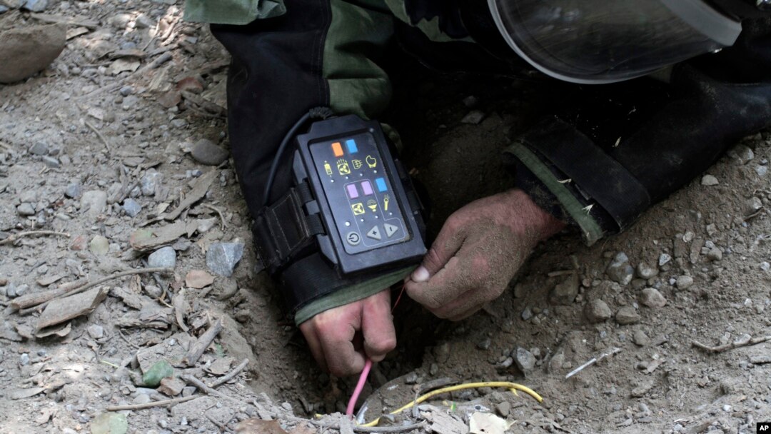 FILE - An Afghan Army soldier searches for land mines with a metal detector during an exercise on defusing improvised explosive devices in Jalalabad, east of Kabul, Afghanistan.