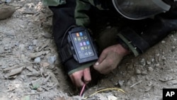 FILE - An Afghan Army soldier searches for land mines with a metal detector during an exercise on defusing improvised explosive devices in Jalalabad, east of Kabul, Afghanistan.