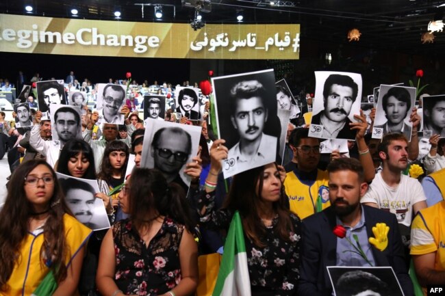 People hold pictures of relatives killed by the Mohllas regime, during "Free Iran 2018 - the Alternative" event, June 30, 2018 in Villepinte, north of Paris during the Iranian resistance national council (CNRI) annual meeting.