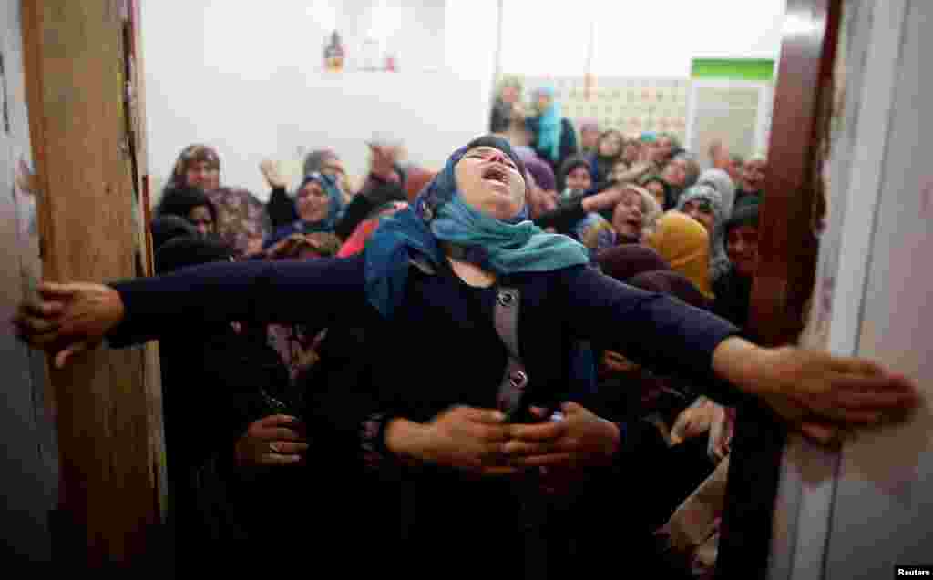 Mourners hold back a relative of Palestinian Hamdan Abu Amshah, who was killed along Israel border with Gaza, during his funeral in Beit Hanoun town, in the northern Gaza Strip.