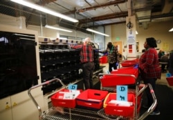 Workers transport sorted Democratic Party ballots into bins to be opened and scanned during the presidential primary at King County Elections ballot processing center in Renton, Washington, March 10, 2020.