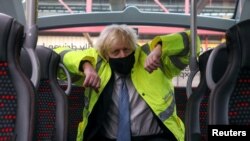 Britain's Prime Minister Boris Johnson sits on a bus during a visit to the National Express depot in Coventry, Britain, March 15, 2021. 