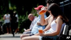Klientët e ulur në stolat jashtë një klubi që ofron pije për t'i marrë me vete, Londër, 23 qershor 2020.