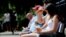People sit in front of a pub that sells take-out drinks, in London, Britain, June 23, 2020. 