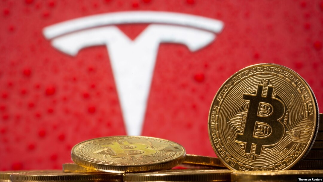 Representación de la moneda virtual Bitcoin vista frente al logo de Tesla. [Foto de archivo]