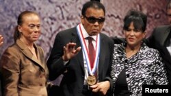 El exboxeador Mohamed Ali saluda luego de recibir la Medalla de la Libertad, el jueves por la noche en Filadelfia. Le acompañan su esposa Lonnie (izquierda) y su cuñada Marilyn Williams.