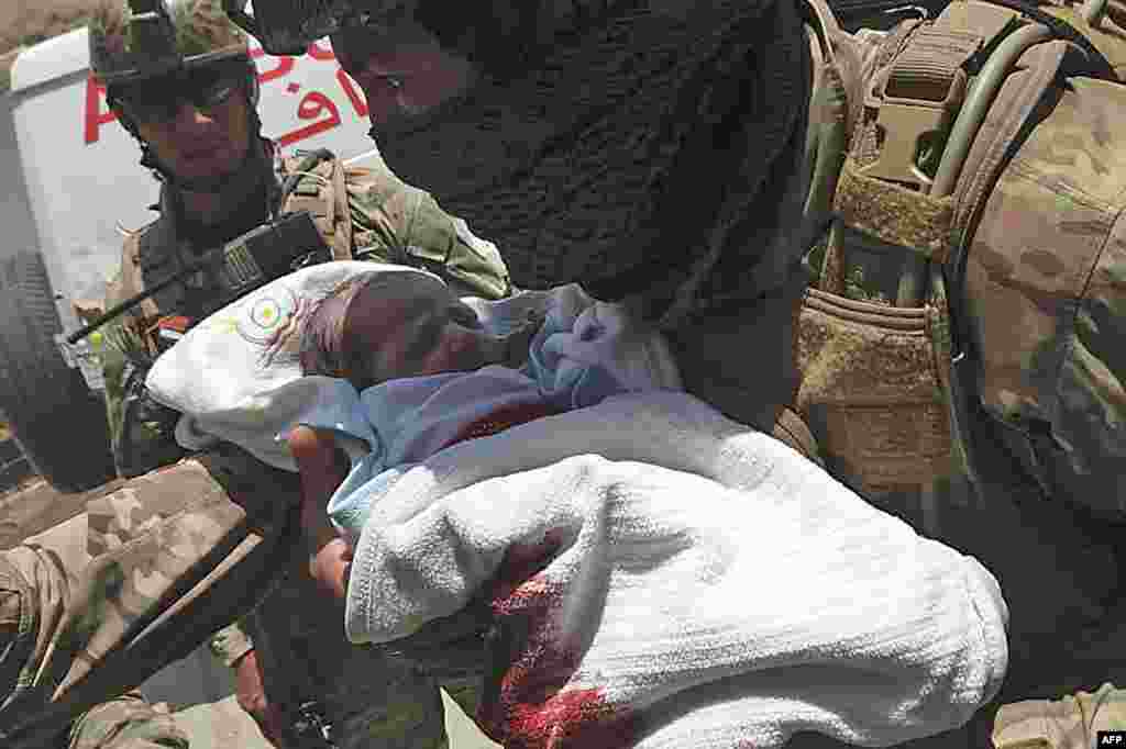 An Afghan security personnel carries a newborn baby from a hospital, at the site of an attack in Kabul. Gunmen stormed the government-run hospital in Dasht-e-Barchi area, killing at least 13 people and injuring 15 others.