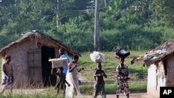 Ivorian refugees walk in the village of Loguatuo as many have flooded into Liberia, (File)