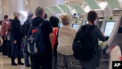 FILE - Passengers arriving from abroad at Los Angeles International Airport use new automated passport kiosks.