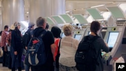 FILE - Passengers arriving from abroad at Los Angeles International Airport use new automated passport kiosks.