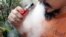 FILE - A man blows a puff of smoke as he vapes with an electronic cigarette, Oct. 18, 2019. 