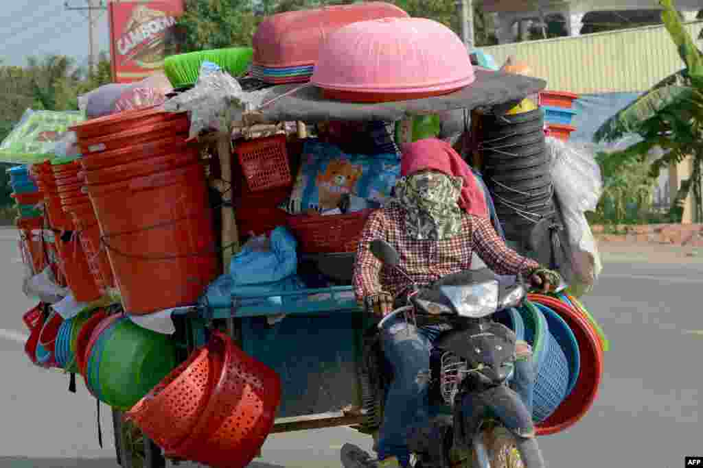 ពលរដ្ឋខ្មែរម្នាក់បើករ៉ឺម៉កម៉ូតូរបស់គាត់ដែលមានសុទ្ធតែឥវ៉ាន់ នៅតាមផ្លូវមួយនៅជាយក្រុងភ្នំពេញ។
