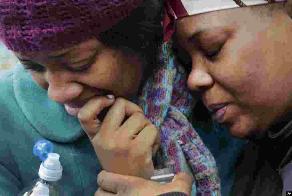 Alecia Thomas, left, is comforted by her friend, Shivon Dollar, after she lost her home following an explosion in Harlem, New York, March 12, 2014. 