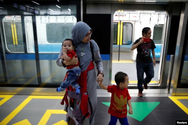 Seorang ibu dan anak-anaknya tiba di stasiun MRT di Jakarta, Indonesia, 12 Maret 2019.