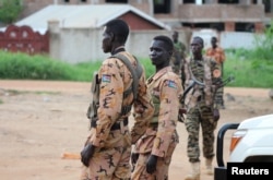 FILE - South Sudanese policemen and soldiers stand guard along a street following renewed fighting in South Sudan's capital Juba, July 10, 2016.