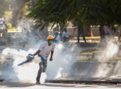 A demonstrator picks up a tear gas canister during protests against Haiti's President Jovenel Moise, in Port-au-Prince, Haiti, Feb. 8, 2021.