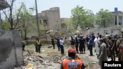A rescue worker and security officials gather at the site after a deadly blast in residential area in Lahore, Pakistan, June 23, 2021. 