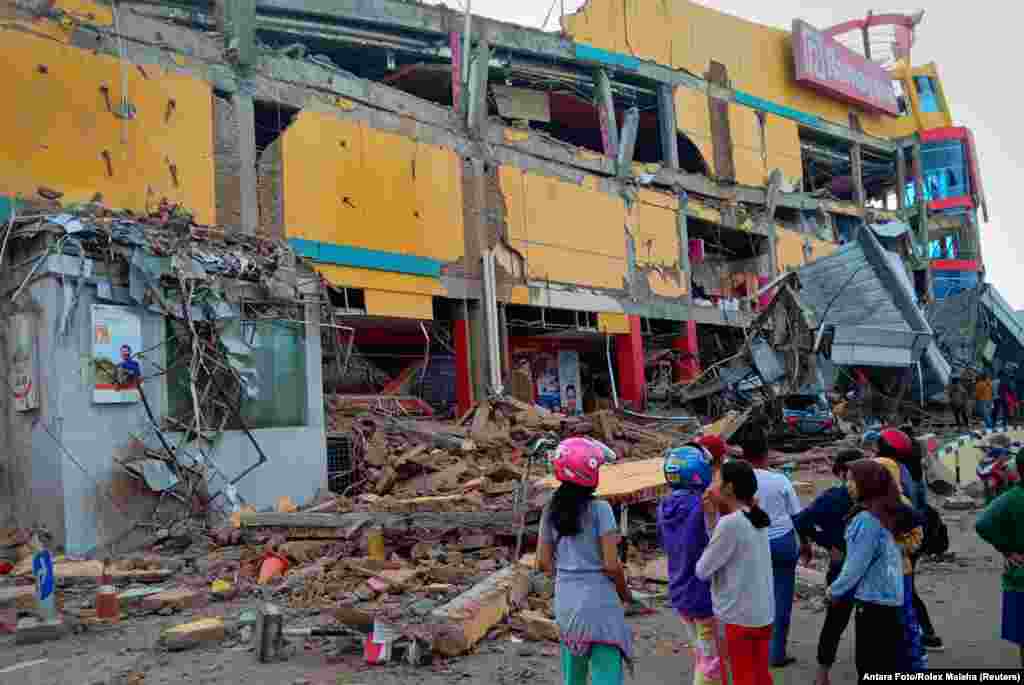Residents stand in front of a damaged shopping mall after an earthquake hit Palu, Sulawesi Island, Indonesia, Sept. 29, 2018.