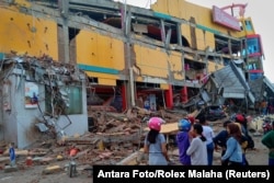 Residents stand in front of a damaged shopping mall after an earthquake hit Palu, Sulawesi Island, Indonesia, Sept. 29, 2018.