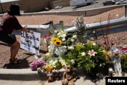 Seorang prempuan meletakkan plakat untuk menghormati para korban penembakan massal di Walmart, El Paso, Texas, AS 4 Agustus 2019.