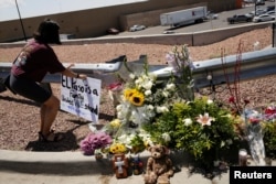 Seorang perempuan meletakkan poster di lokas penembakan massal yang menewaskan 20 orang di toko Walmart di El Paso, Texas, 4 Agustus 2019. (Foto: Reuters)